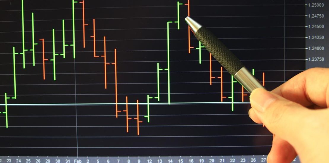 Pen point on screen with background bar chart trading.