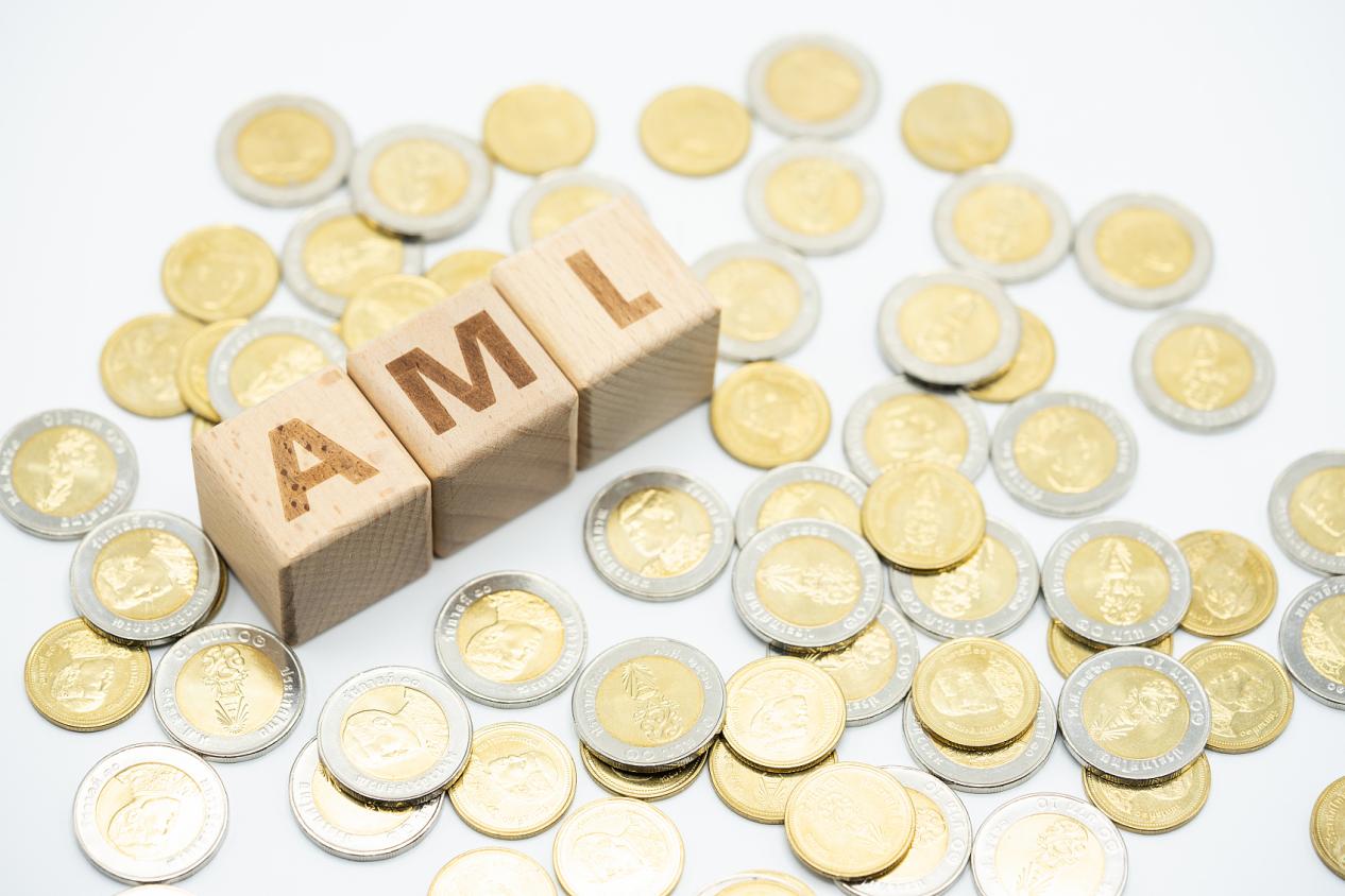 Money laundering concept, wooden word block 'AML' on plie of coins.