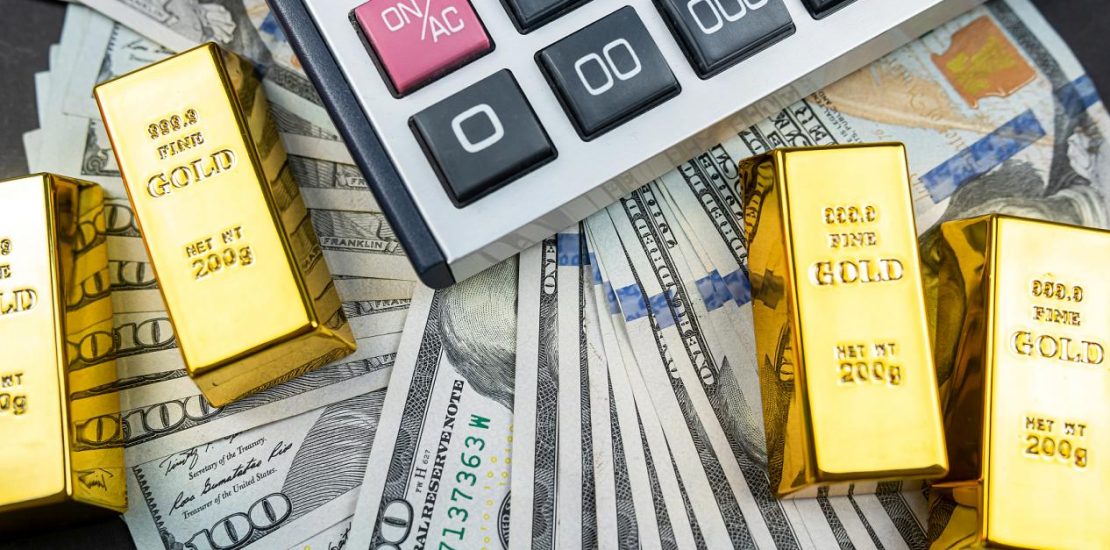 金条和计算器躺在一大堆孤立的美元旁边。