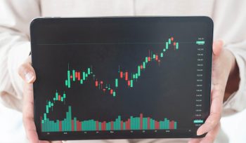 商业女性手拿数字平板电脑与图表二元期权交易平台,搜索重点